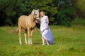 Rider woman blonde with long hair in a white dress with a train posing on a palamino horse Royalty Free Stock Photo