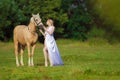 Rider woman blonde with long hair in a white dress with a train posing on a palamino horse Royalty Free Stock Photo