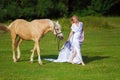 Rider woman blonde with long hair in a white dress with a train posing on a palamino horse Royalty Free Stock Photo