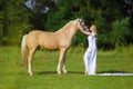 Rider woman blonde with long hair in a white dress with a train posing on a palamino horse Royalty Free Stock Photo
