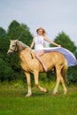 Rider woman blonde with long hair in a white dress with a train posing on a palamino horse Royalty Free Stock Photo