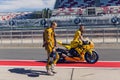 Rider yellow suit and helmet, and technical personnel to carry the bike around the pits after the race