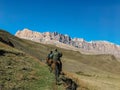 Riders on horseback ride in the mountains during the daytime rear view