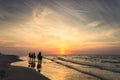 Riders on horseback riding along the seashore at sunset