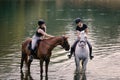 Riders, two young women riding horses down the river Royalty Free Stock Photo