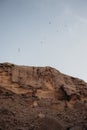 A ridge made of shell rock on the background of blue skies with silhouettes of flying birds Royalty Free Stock Photo