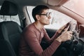 Ridiculous and idiotic nerd driver is staring at the road and holding the steering wheel. Concept of a novice driver and Royalty Free Stock Photo