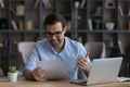 Laughing young man editor reading printed draft of funny article