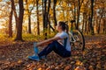 Riding bicycle in autumn forest. Young woman having rest after workout on bike. Healthy lifestyle Royalty Free Stock Photo