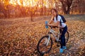 Riding bicycle in autumn forest. Young woman having rest after workout on bike holding water bottle. Healthy lifestyle Royalty Free Stock Photo