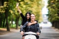 Riding with fun. Beautiful young couple riding scooter together while happy woman raising arms and smiling. Ride and love Royalty Free Stock Photo