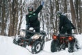 Riding the opposite ways. Two people are on the ATV in the winter forest