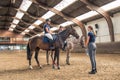 Girls on horses with instructor inside riding school, The Netherlands