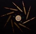 Rifle ammo with a lot of gemstones around one euro coin on black background. Symbolizes the war for money and one of the world`s p Royalty Free Stock Photo