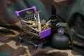 Rifle cartridges in small shopping cart. Big caliber ammo cartridges and hand grenades with a small shopping basket