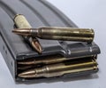 A rifle magazine loaded with 223 caliber bullets with two separate bullets on top of it Royalty Free Stock Photo
