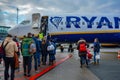 A crowd of travellers in front of Ryanair airplane, passengers waiting outside aircraft for boarding
