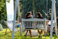 Two women sitting on park swing and talking, view from behind, Riga, Latvia