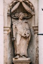 Riga Latvia. Close Ancient Statue Of Man With Cross And Book In Hands On The Facade Of St. Peter Church,