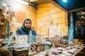 Riga, Latvia. Man Seller Sells Various Natural Wooden Crafts At Winter Christmas Market