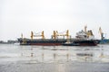 Multiple tugboats work in tandem to assist cargo ship to maneuver out of the port