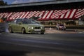 12-05-2022 Riga, Latvia a green car driving down a race track with a person watching from the side of the track behind it