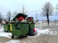 Riga, Latvia - 4 January, 2024: Trash cans on a city street overflowing with waste, garbage and bags.