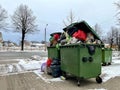 Riga, Latvia - 4 January, 2024: Trash cans on a city street overflowing with waste, garbage and bags.