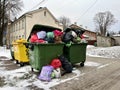 Riga, Latvia - 4 January, 2024: Trash cans on a city street overflowing with waste, garbage and bags.