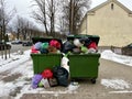 Riga, Latvia - 4 January, 2024: Trash cans on a city street overflowing with waste, garbage and bags.