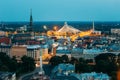 Riga, Latvia. Aerial View Of Cityscape In Evening Night Lights Illumination. Summer Top View Of St. Peter`s Church