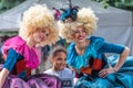 Beautiful couple of girls in vintage funny colourful clothes and wigs taking a photo with a black little girl