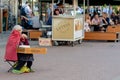 RIGA, LATVIA - JULY 26, 2018: An old woman is sitting on the street, playing music and earning money.