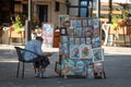 RIGA, LATVIA - JULY 31, 2018: Souvenir vendor on the street sits in a chair and read a book.