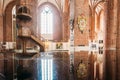 Riga Latvia. Wooden Pulpit In Interior Of St. Peter Church, Reflected On Black Glossy Piano Surface