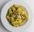 Rigatoni carbonara with peas on white plate classic italian pasta dish