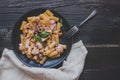 Rigatoni pasta with sea food and basil on the wooden black table, top view