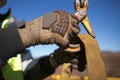 Rigger high risk worker wearing heavy duty glove and clipping a crane hook into yellow three tones lifting sling prior to lift