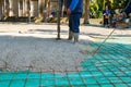 Rigger holding pump hose to pouring fresh concrete, other worker is using hook to pull up square reinforcing steel bars