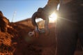 Rigger wearing a safety glove holding crane lifting 17 tone shackle with defocused crane at the back ground during sunset