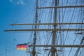 Rigging and masts of a big sailing ship in front of a blue sky with the black-red-golden flag of the state Germany, ship Royalty Free Stock Photo