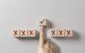 right choice concept. businessman hand selects wooden cube with green tick against background of incorrect cubes with cross. Gray