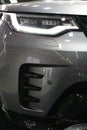 Right elegant headlight and part of massive front mask of premium english large SUV car Land Rover Discovery