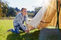 Right, first step pitching the tent. a young boy putting up his tent on a camping trip.