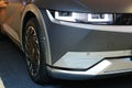 Right front view of partially lit headlights and right front wheel of korean battery electric compact crossover SUV