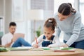 With the right guidance, she can do great things. a young mother helping her daughter with her homework at home. Royalty Free Stock Photo