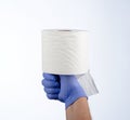 Right hand in blue glove holding with thumb a roll of toilet paper Royalty Free Stock Photo