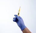 Right hand in blue glove holding a yellow medical thermometer Royalty Free Stock Photo