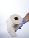 Right hand in blue glove holding a roll of toilet paper Royalty Free Stock Photo