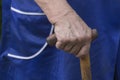 Hand of an elderly woman holding a wooden crutch